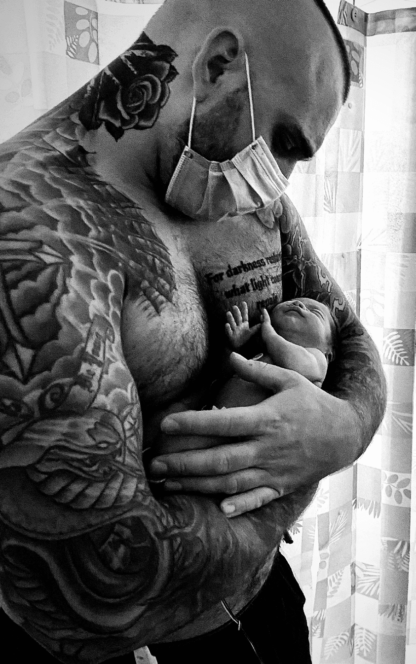 Barnaby in NICU mask holding his premature newborn son